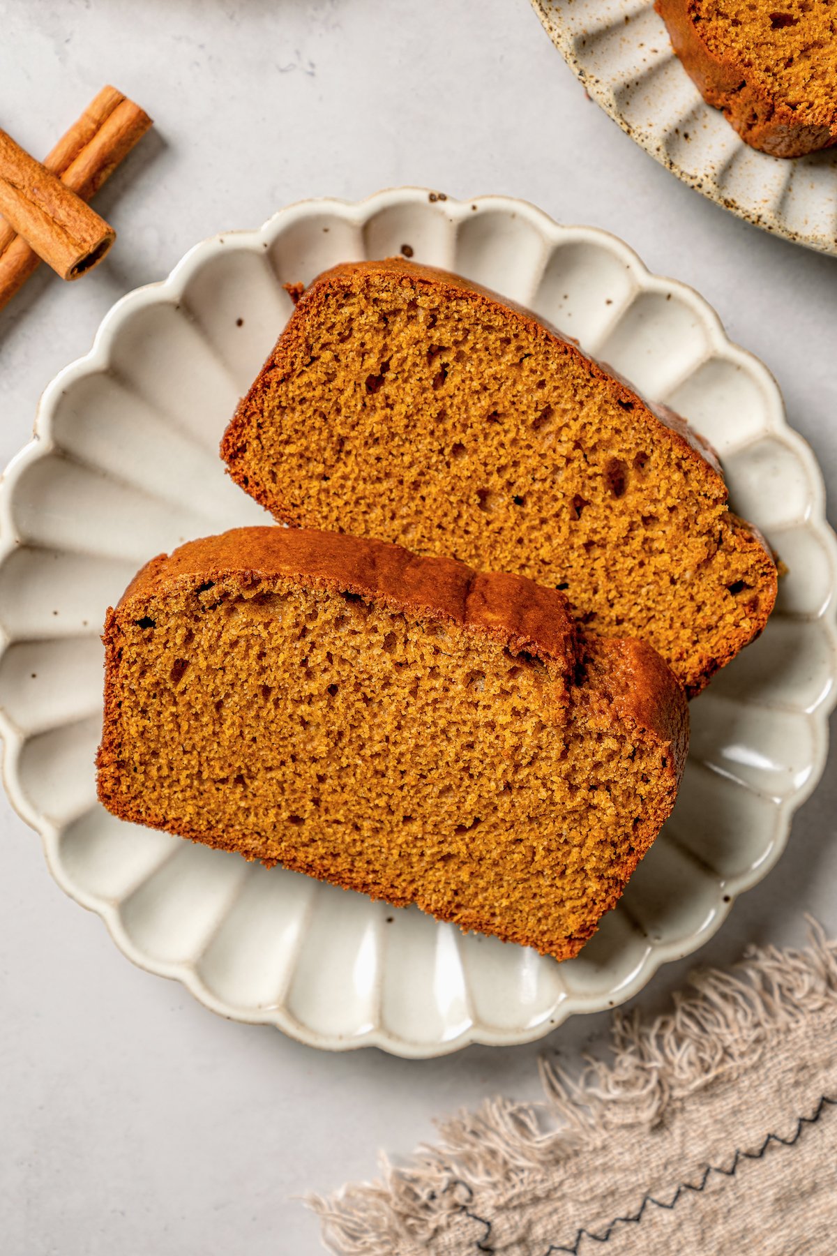 Two slices of pumpkin breakfast loaf with warm spices and brown sugar. 